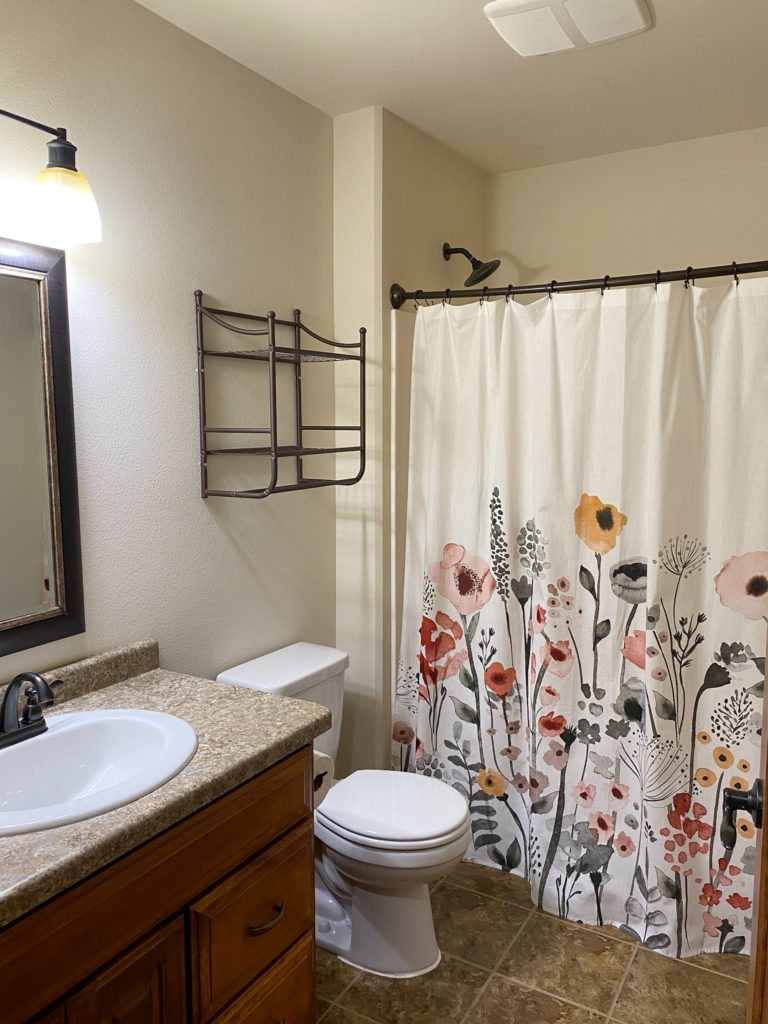 Another view of bathroom to be renovated featuring a floral shower curtain