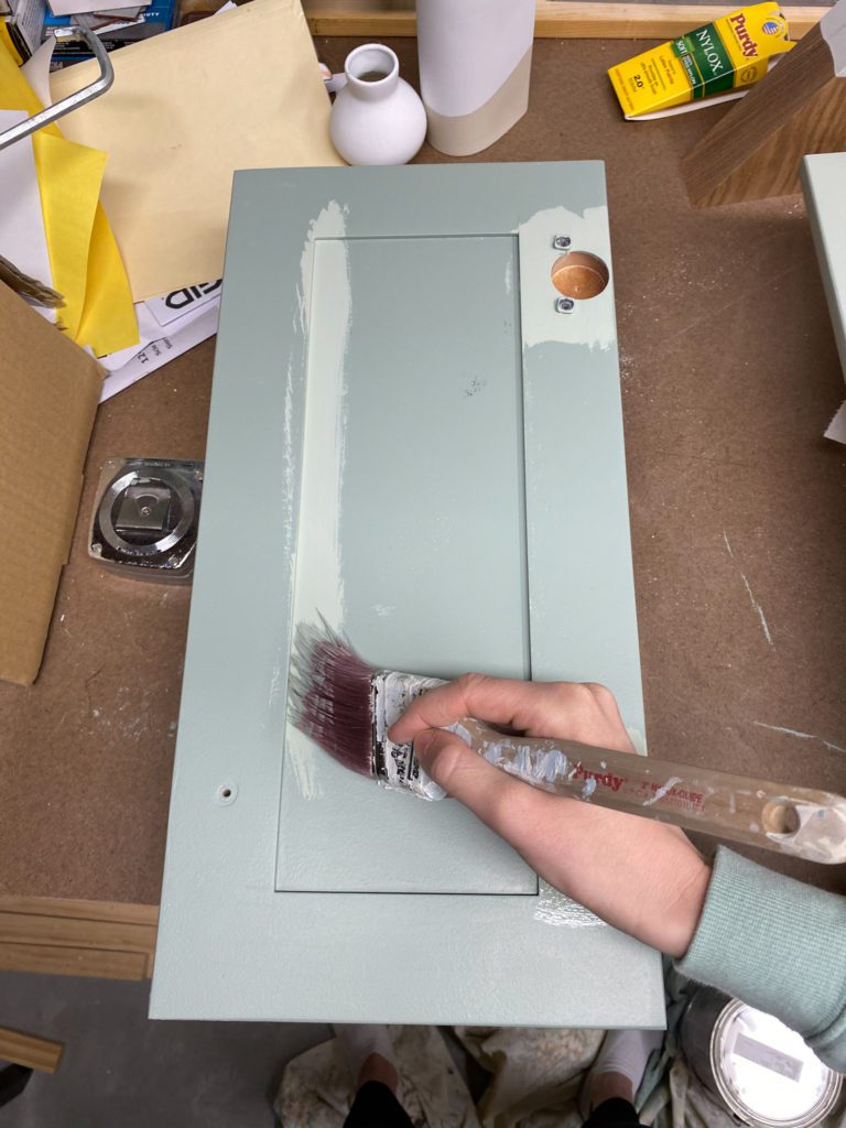 Applying a second coat of paint to bathroom vanity