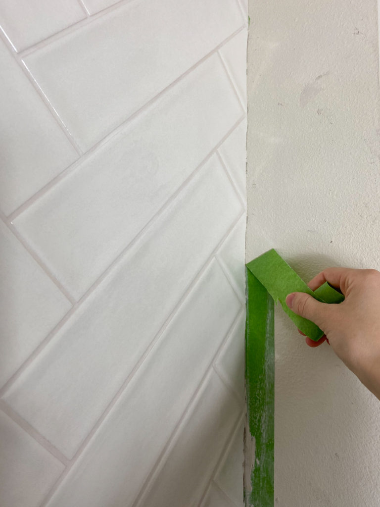 Peeling off painter's tape from edge of tile