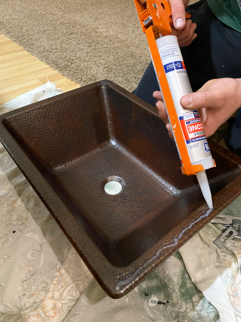 Applying silicone to sink to adhere to countertop