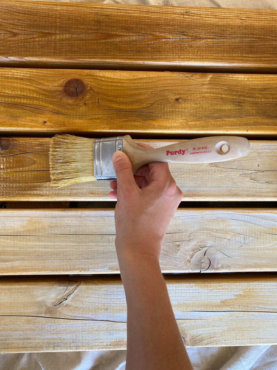 Applying Oil to Outdoor Furniture with a White Bristle Brush